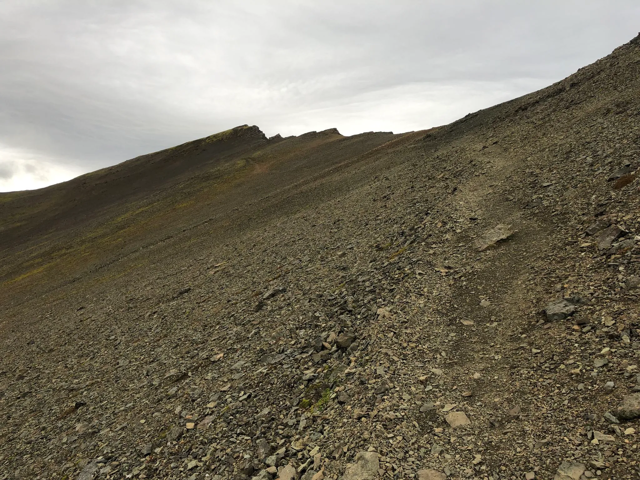 A stony trail following a mountain ridge line toward the summit