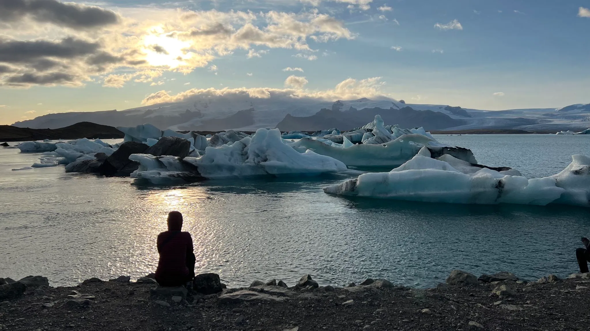 A figure sitting alone at the iceberg lagoon at sunset