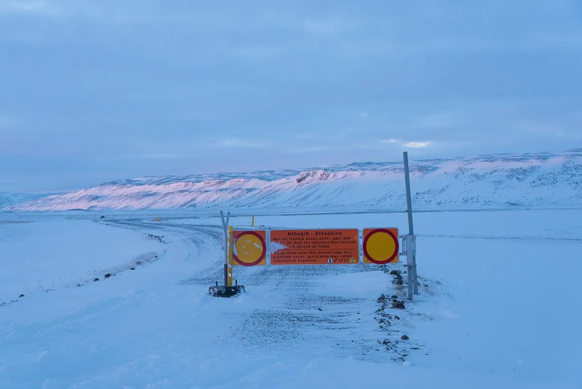 Road closure barrier across a snowed-in road at winter dusk